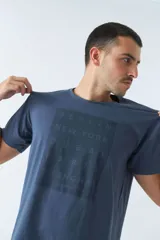 Remera azul de algodón con cuello redondo y estampado frontal con nombres de ciudades: Berlín, Nueva York, Dubai, París y Shanghái.