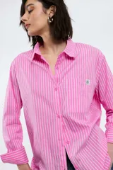 Camisa oversize de popelina a rayas celestes y blancas, con cuello camisero, manga larga con puños abotonados, cierre frontal con botones y un bolsillo en el pecho con etiqueta bordada.