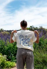 Remerón color crema con estampado en la espalda de dos manos con ojos en las palmas y estrellas azules.