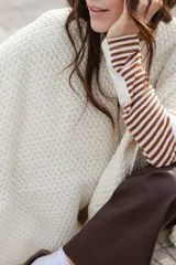 Ruana tejida en lana merino color ladrillo, con textura de punto grueso.