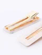 Set de dos broches rectangulares para el pelo con diseño de carey en tonos crema y blanco, y gancho dorado.