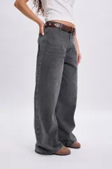 Pantalón jean ancho color gris claro, de corte holgado y tiro medio con estampa circular en el bolsillo trasero.