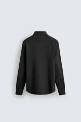 Camisa de corte relajado confeccionada en tejido de algodón con textura. Presenta cuello italiano, manga larga con puños abotonados y cierre frontal mediante botonadura.