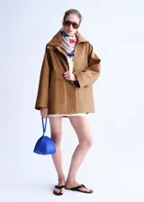 Chaqueta oversize color tostado con cuello embudo, manga larga, bolsillos laterales y bolsillos de parche con solapa. Cuenta con cierre delantero de cremallera y botones ocultos bajo tapeta, y forro interior.