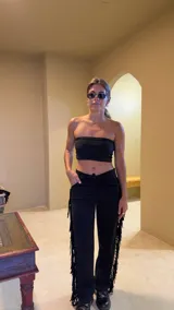 Pantalón negro de gamuza con flecos en los laterales, tiro alto y ajuste con cordones.