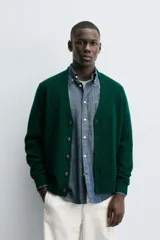 Cárdigan de punto en color verde oscuro, con cuello en pico, manga larga y cierre frontal con botones. Presenta acabados en rib en puños y bajo.