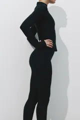 Campera deportiva de corte ajustado en tejido funcional con tecnología de absorción de sudor. Presenta cuello elevado, cierre frontal completo, mangas raglán extralargas con abertura para el pulgar y bolsillos laterales con cierre.
