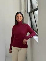 Polera de punto color bordó con cuello alto, manga larga y puños acanalados.