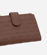 Billetera femenina pequeña de material sintético color marrón, con textura grabada y cierre de cremallera con solapa con broche a presión.