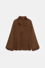 Blusa de cuello subido con diseño de lunares, manga larga abullonada con puños elásticos y forro interior.