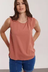 Blusa color salmón sin mangas con detalle de drapeado en el hombro.