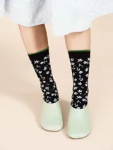Medias de algodón color negro con estampado de flores blancas y borde superior verde.