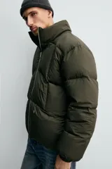 Cazadora acolchada de corte relajado confeccionada en tejido técnico color verde militar. Presenta cuello subido, cierre frontal con cremallera, mangas largas con puños elásticos y bolsillos frontales con cremallera oculta.