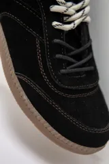 Zuecos de cuero negro con diseño tipo sneaker, cordones y suela de goma color caramelo. Presentan detalle de marca Petra en la lengüeta.