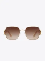 Lentes de sol Carolina Lemke con montura cuadrada dorada y lentes marrones degradé.