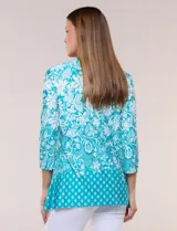 Blusa azul y blanca con estampado floral y geométrico, de calce suelto, con escote redondo, abertura tipo keyhole en el pecho, mangas tres cuartos y ruedo amplio con silueta evasé.