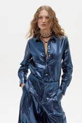 Camisa de manga larga con cuello clásico y cierre frontal de botones, confeccionada en lino con acabado metalizado brillante.