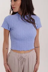 Blusa lavanda de mangas cortas con textura arrugada y cuello alto.