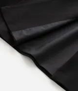 Chaleco sastre de corte alargado, color negro, con escote en V profundo y diseño sin mangas. Presenta un estilo minimalista con bolsillos laterales simulados y ajuste entallado en la espalda.