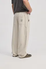 Pantalón de algodón color beige, de corte holgado y pierna amplia, con cintura elastizada y cordón ajustable.