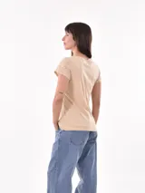 Remera de manga corta color beige claro, con cuello redondo y detalles de bordado tipo ojal (broderie) en las mangas.