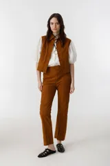 Pantalón de gamuza color marrón, de corte recto, con cierre lateral plateado, forro interno con stretch y tajos en el dobladillo.