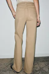 Jeans de tiro alto con corte wide leg y largo completo. Presenta diseño de cinco bolsillos, trabillas en la cintura y cierre frontal con cremallera y botón, con un acabado de efecto lavado.