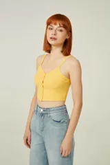 Top amarillo de breteles finos, confeccionado en poliéster de punto canalé, corte al cuerpo, con botones y cuello en V.