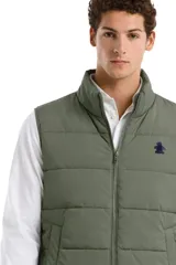 Chaleco puffer de cuello alto con cierre frontal, diseño acolchado horizontal y logo bordado en el pecho.