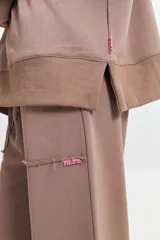 Buzo de felpa color marrón con estampa frontal en rosa, cuello redondo y hombros caídos.