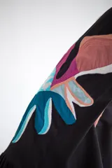 Vestido midi color verde oliva, sin mangas, con escote redondo y detalle de estampado floral en el lateral.