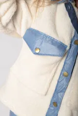 Chaqueta color crema de corderito con detalles en jean azul en cuello, solapa, bolsillos y puños.