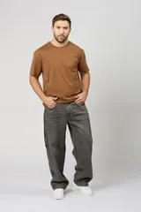 Pantalón de jean estilo baggy con corte holgado y diseño de carpintero, en color gris oscuro con efecto lavado. Presenta costuras reforzadas en contraste y bolsillos laterales funcionales.