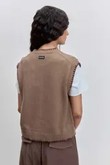 Chaleco de punto color marrón con cierre frontal de botones y detalle de costuras en contraste en los bordes. Presenta un diseño de cuello redondo y corte recto.