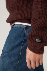 Sweater de punto con textura waffle, cuello redondo y mangas largas. Presenta un pequeño parche con logo en el puño izquierdo.