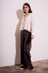 Blusa blanca de algodón con escote en V, mangas largas con detalles de encaje y cierre frontal con lazos.