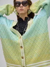 Cardigan de punto con diseño degradé en tonos tierra, patrón de rombos en relieve, cuello en V con cartera de botones y puños con rayas blancas y marrones.