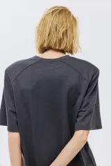 Remera gris oscuro de manga corta con cuello redondo y costuras oblicuas en los hombros.