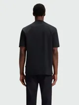 Remera de corte regular, color negro, con cuello redondo y detalle de monograma metálico en el pecho.