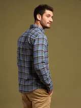 Camisa celeste a cuadros con cuello abotonado, manga larga y bolsillo en el pecho.