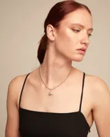 Dije con forma de corazón plateado con detalles grabados.