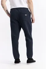 Pantalón de jogging negro de algodón y poliéster, con puños ajustados en los tobillos, cintura elástica con cordón y costuras verticales marcadas en el frente.