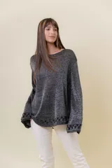 Suéter tejido en hilo con efecto lurex, color gris oscuro con brillo plateado. Presenta cuello redondo, mangas amplias y puños y ruedo con detalle de tejido en patrón geométrico.