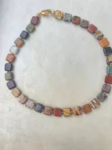 Collar de piedras naturales con piezas cuadradas en tonos tierra, ocres y terracotas, con vetas únicas.