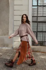 Falda midi de diseño asimétrico que combina un panel de tela escocesa en tonos verdes, blancos y marrones con un panel lateral de paño verde oscuro. Presenta un tajo lateral pronunciado y tiro a la cintura.