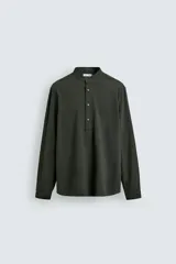 Camisa de corte relajado confeccionada en una mezcla de algodón y modal con acabado efecto arrugado. Presenta cuello tipo tira, cierre frontal con botonadura parcial y manga larga con puños abotonados.