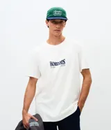 Remera masculina blanca de manga corta y cuello redondo, con estampa en la espalda de una tabla de surf, olas y la inscripción "Horizons".