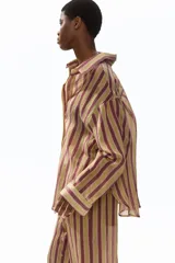 Camisa H&M de corte oversized en mezcla de lyocell, con estampado de rayas verticales en tonos bordó, beige y verde oliva. Presenta cuello camisero, abertura frontal con botones, hombros caídos y mangas largas con puños abotonados.