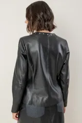 Campera de cuero color camel, con cuello redondo, cierre frontal y detalles de tachas metálicas en el cuello y bolsillos laterales.