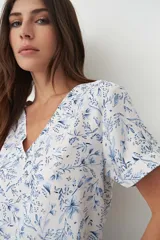 Blusa blanca con estampado floral celeste, escote en V y mangas cortas.